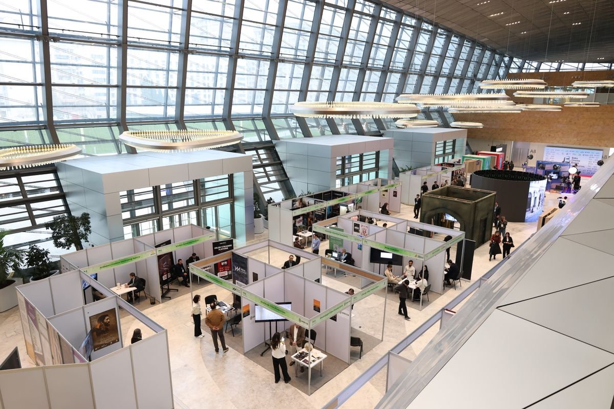 A busy exhibition hall with rows of booths and visitors walking between them