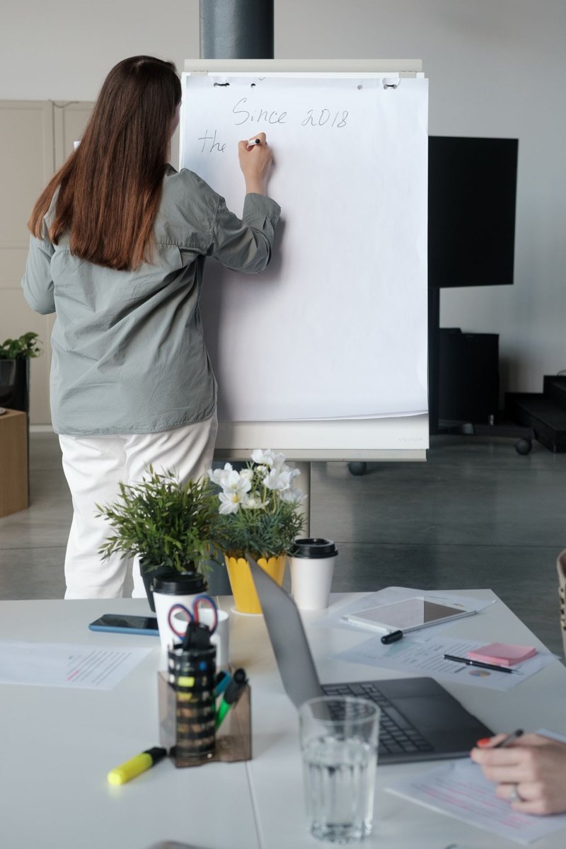 A woman writing notes on a flip chart pad during a meeting in an office